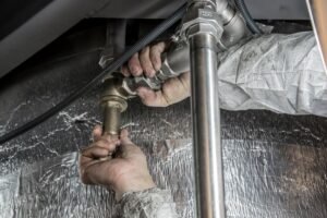 Plumber working on pipes in Houston home