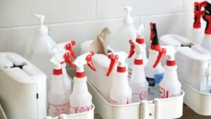Caddy of white cleaning spray bottles and supplies